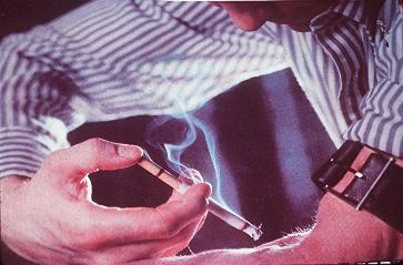 A male nicotine addict injecting nicotine via a cigarette into his arm