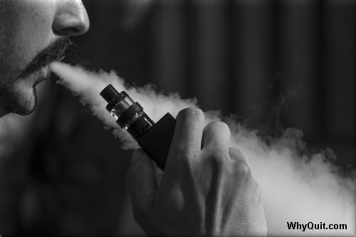 An man vaping from an e-cigarette tank.