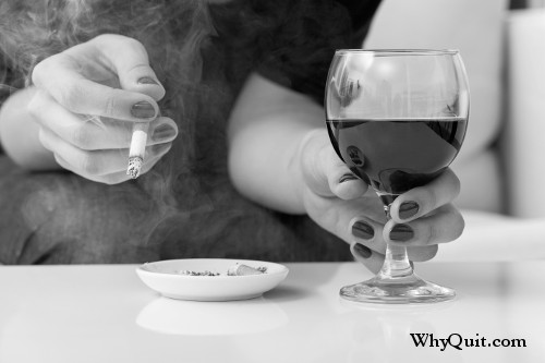 Photo of a woman drinking wine while smoking a cigarette.