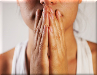 Woman putting her hands to her mouth as if in prayer.