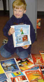A child making a face while holding up and showing a Time magazine page containing a Camel cigarette advertisement