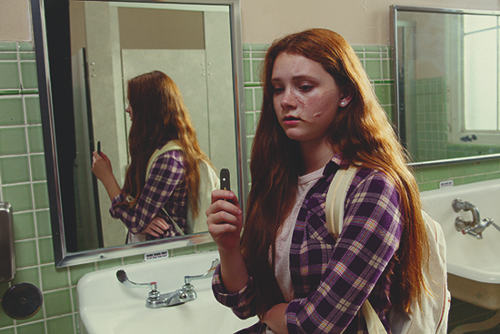 FDA photo of a teenage girl holding a Juul while vaping in a school bathroom