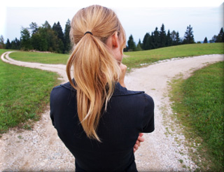 Woman looking at a fork in a dirt road.  Which path to take, continue trying to quit smoking or go back to smoking>