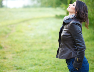 Woman standing in a field while taking a deep breath