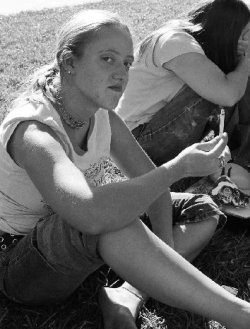 A college student looking at her cigarette as if she didn't smoke.