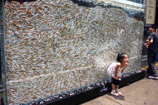 A little girl standing in front of a tank filled with thousands of cigarette butts.