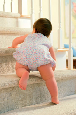 A baby climbing stairs just one stair at a time.