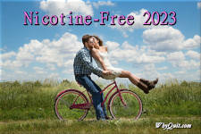 A young bearded smiling man in jeans and a blue plad long sleeved shirt riding a pink lady's bike while woman sitting on the handle bards leans back to kiss him on the left cheek while wearing a short white dress and brown cowboy boots and they ride along a grassy path. The image is captioned Nicotine-Free 2023.