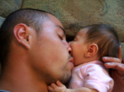 Picture of Quentin Delgado lying with his baby daughter before being diagnosis with kidney cancer.