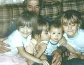 A picture of Holly, her brother and two cousins sharing grandpa's embrace